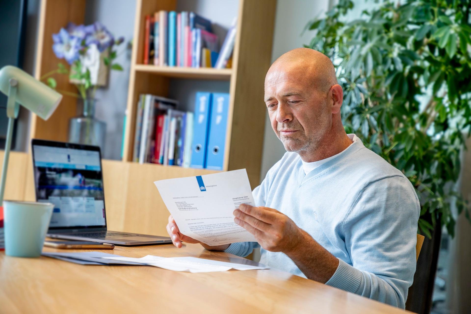 Man zit bij zijn laptop en leest Belastingdienst brief